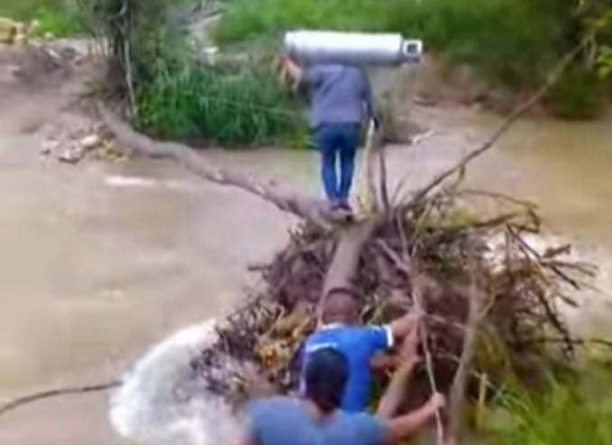 Intentan cruzar el río cargando un cilindro de gas